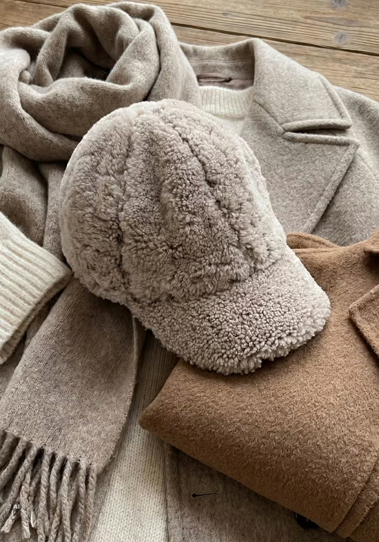Lammfell-Cap in Camel als liegende Detailansicht mit weicher, lockiger Oberfläche.