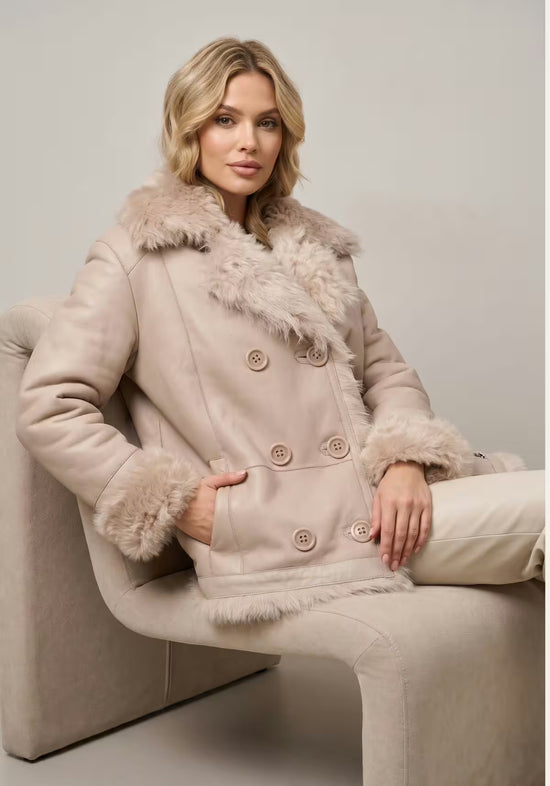 Beige Wendejacke aus Curly-Lammfell, getragen mit glatter Lederseite und Fellbesatz.