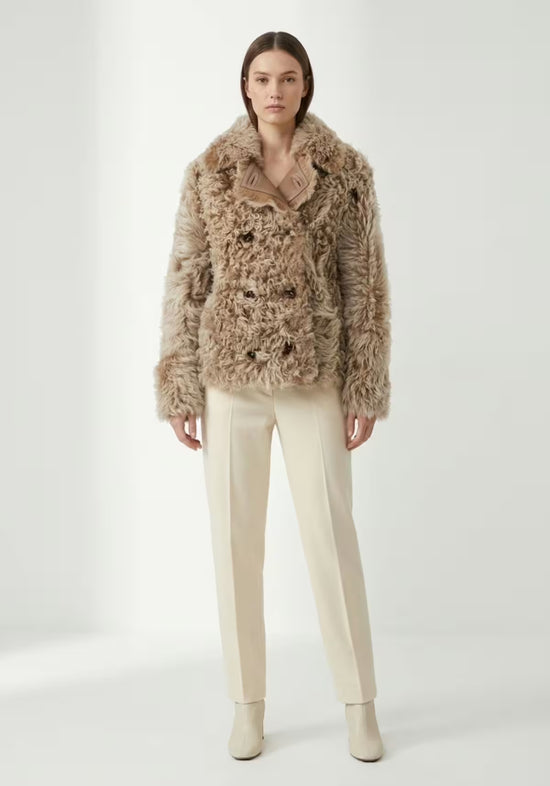 Damen-Curly-Lammfelljacke in Cappuccino frontal an einer Modelldarstellung mit heller Hose.