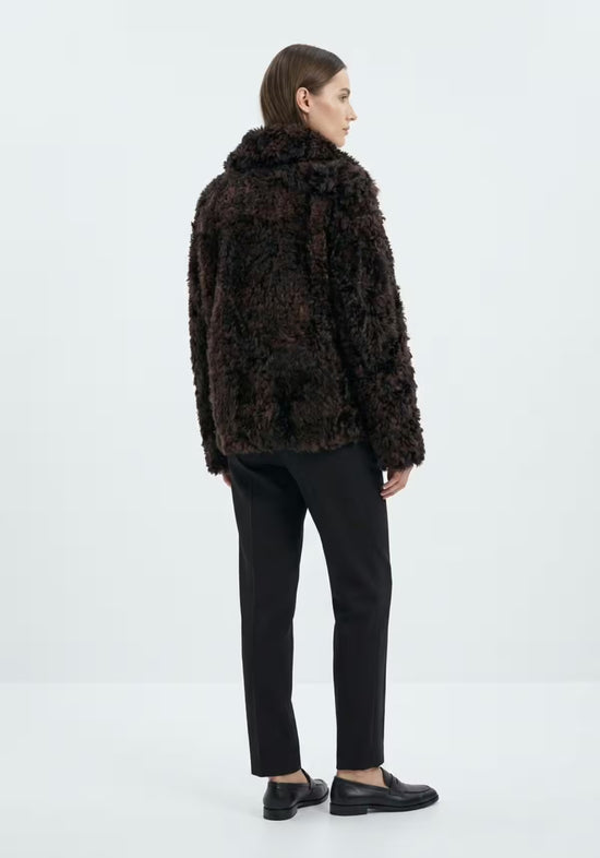 Damen-Curly-Lammfelljacke in Dunkelbraun, von hinten am Modell mit kurzem Schnitt.