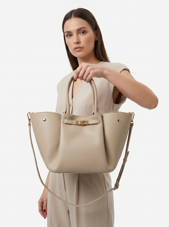 Damen-Handtasche aus Leder in Cremebeige, von einer Frau getragen mit Schulterriemen im Studio.