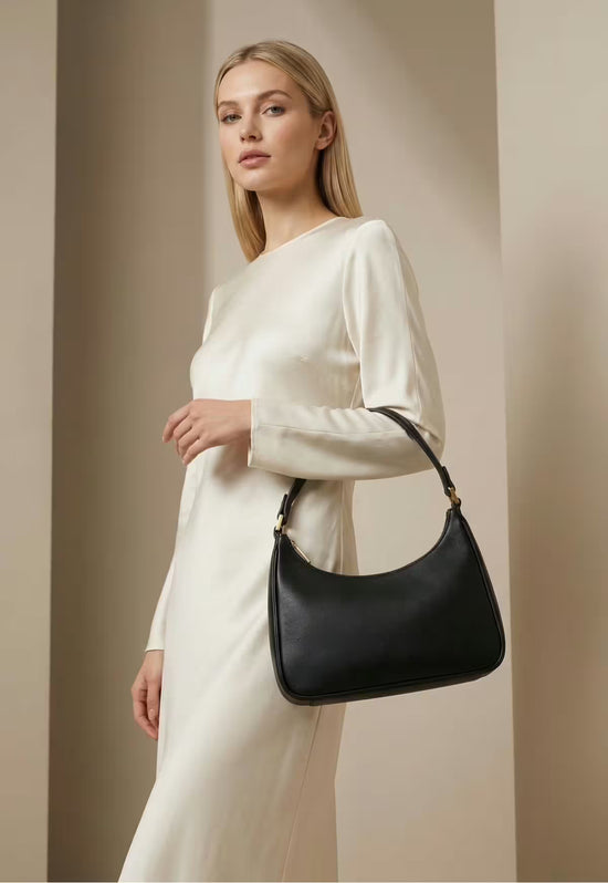 Schwarze Leder-Handtasche für Damen seitlich getragen an einem hellen Kleid