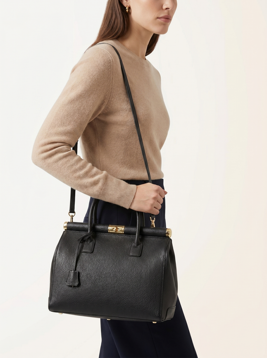 Schwarze Damen-Handtasche aus Leder seitlich an einer Frau mit langem Trageriemen