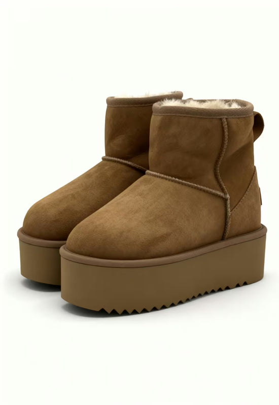 Paar brauner Lammfell-Stiefeletten mit sichtbarem Fellrand und hoher Plateausohle.