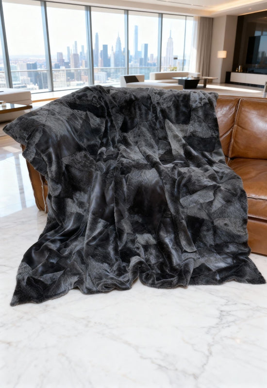 Groß ausgelegte graue Lammfelldecke aus Merino auf dem braunen Sofa im Wohnzimmer.