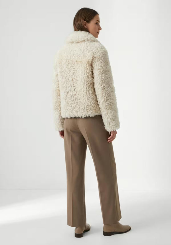 Cremefarbene Curly-Lammfelljacke für Damen von hinten getragen, mit geradem Saum und langen Ärmeln