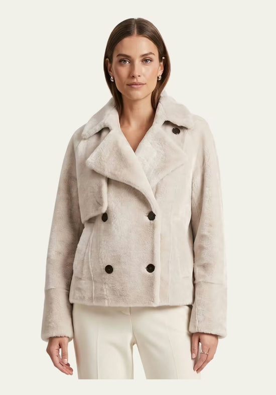 Creme-beige Lammfelljacke für Damen an einem Model, vorne getragen mit breitem Revers und langen Ärmeln.