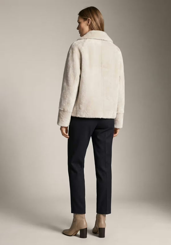 Rückansicht der creme-beigen Lammfelljacke für Damen mit geradem Schnitt und glatter Rückenpartie.
