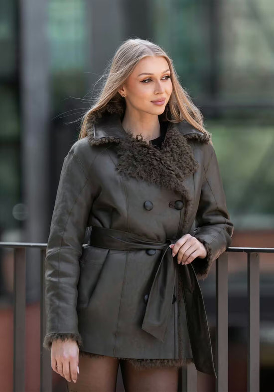 Lammfelljacke für Damen in Oliv mit glatter Lederseite außen, Gürtel und Fellbesatz am Kragen.