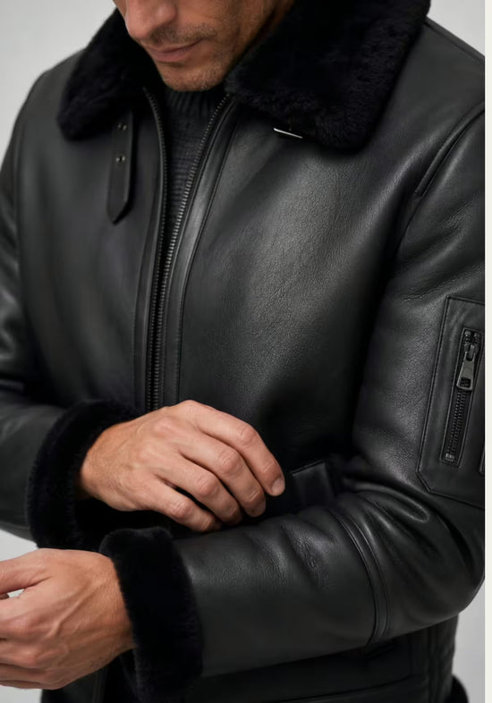 Detail der schwarzen Lammfelljacke für Herren mit Ärmel, Reißverschluss-Tasche und Lammfellbesatz.
