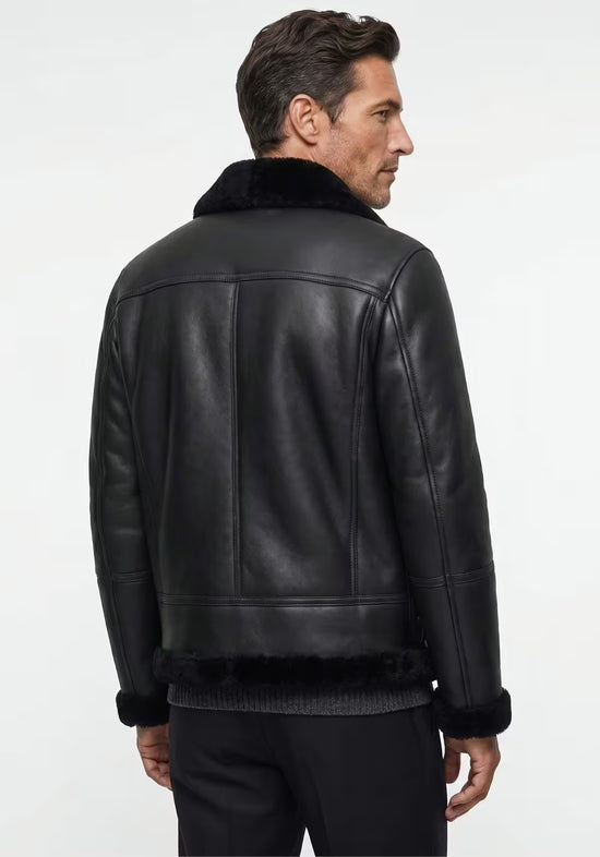 Schwarze Herren-Lammfelljacke am Modell von hinten, mit glattem Rückenteil und Lammfellsaum.