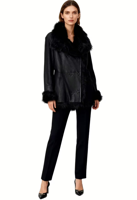 Schwarze Lammfelljacke für Damen, am Modell getragen mit weitem Kragen und schmaler Hose.