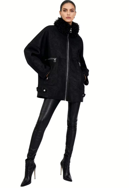 Schwarze Damen-Lammfelljacke am Model in Frontansicht, mit Curly-Kragen, Zippertaschen und schmaler Silhouette.