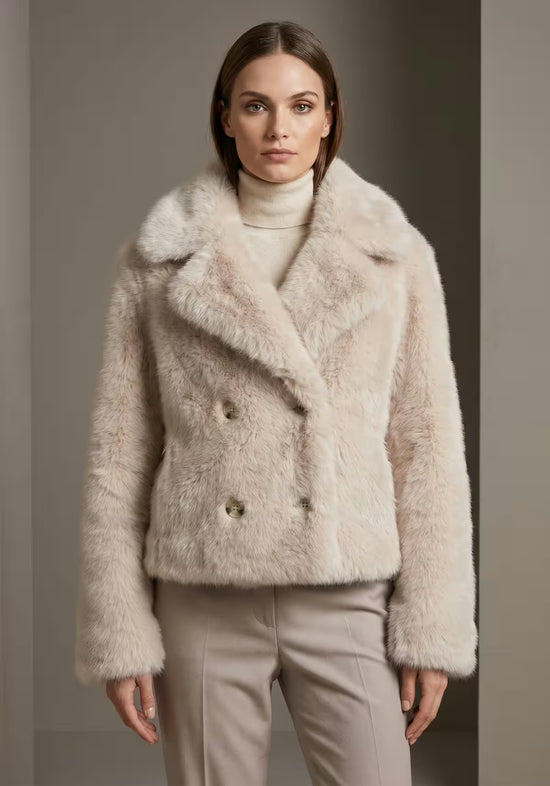 Damen-Lammfelljacke aus Sheepskin in Creme-Beige, als Porträtansicht vor dunklem Hintergrund.