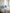 Zwei himmelblaue Lammfellkissen liegen auf dem hellen Bett neben der Leinenbettdecke