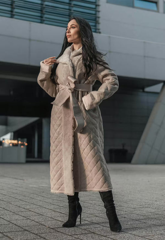 Damen-Lammfellmantel in Beige in voller Länge, seitlich getragen mit offenem Vorderteil und Gürtel.
