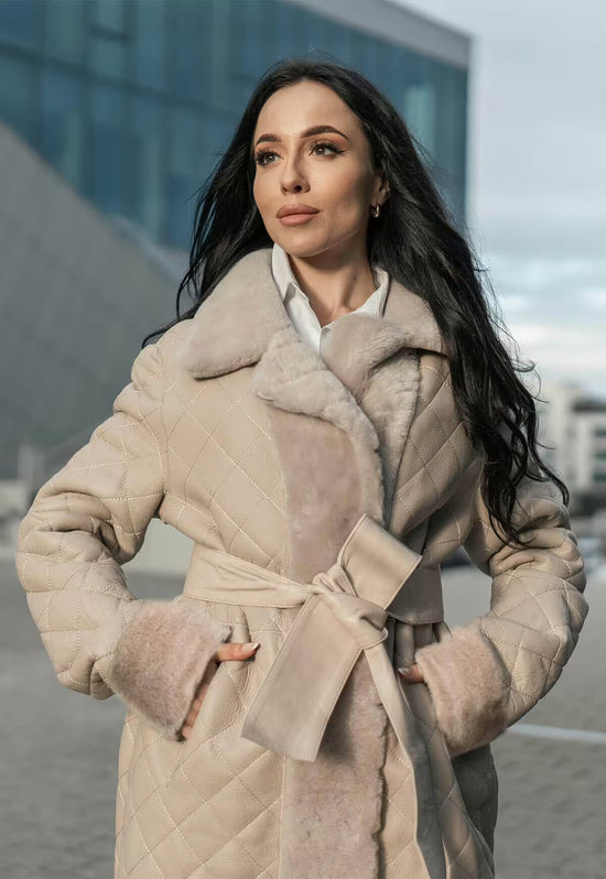 Damen-Lammfellmantel in Beige als Trageansicht mit Gürtel, Kapuze und breitem Revers.