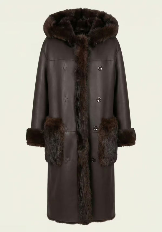 Brauner Lammfell-Wendemantel für Damen mit Knopfleiste, Kapuze und aufgesetzten Taschen.