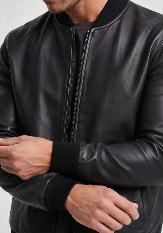 Detail der Herren-Lederjacke aus schwarzem Lammnappaleder mit Reißverschluss, Ärmelbund und glatter Oberfläche.