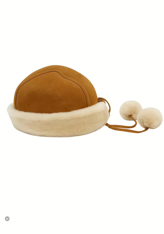 Freigestellte Damen-Mütze aus Lammfell und Merino in Whisky mit Fellrand und Bändern mit Bommel.