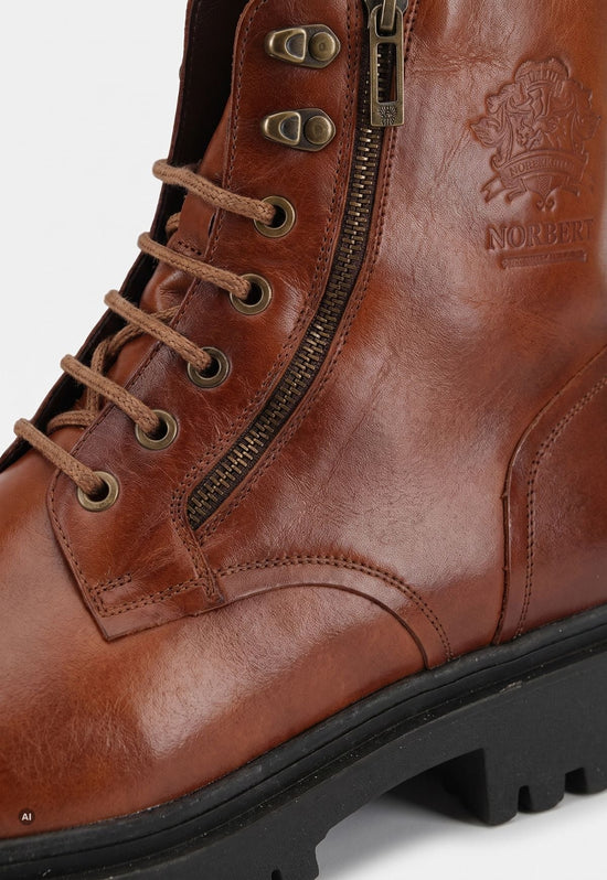 Detail der braunen Herren-Lammfell-Stiefelette mit Reißverschluss, Schnürösen und Lederprägung.