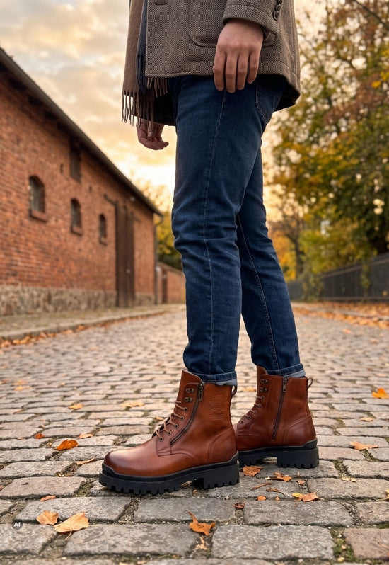 Braune Herren-Lammfell-Stiefeletten getragen im Outdoor-Einsatz zu Jeans auf Kopfsteinpflaster.