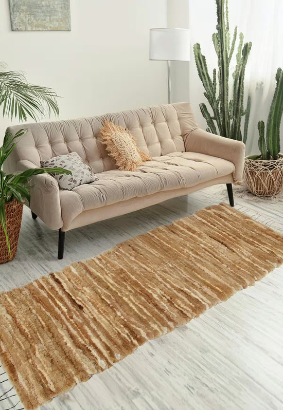Honigfarbener Woll-Läufer vor beigem Sofa in einem hellen Wohnraum.