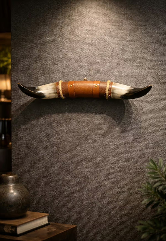 Bullenhorn-Wanddeko mit Leder-Holzhalterung an strukturierter Wand, im Wohnraum mit Dekoobjekten inszeniert.